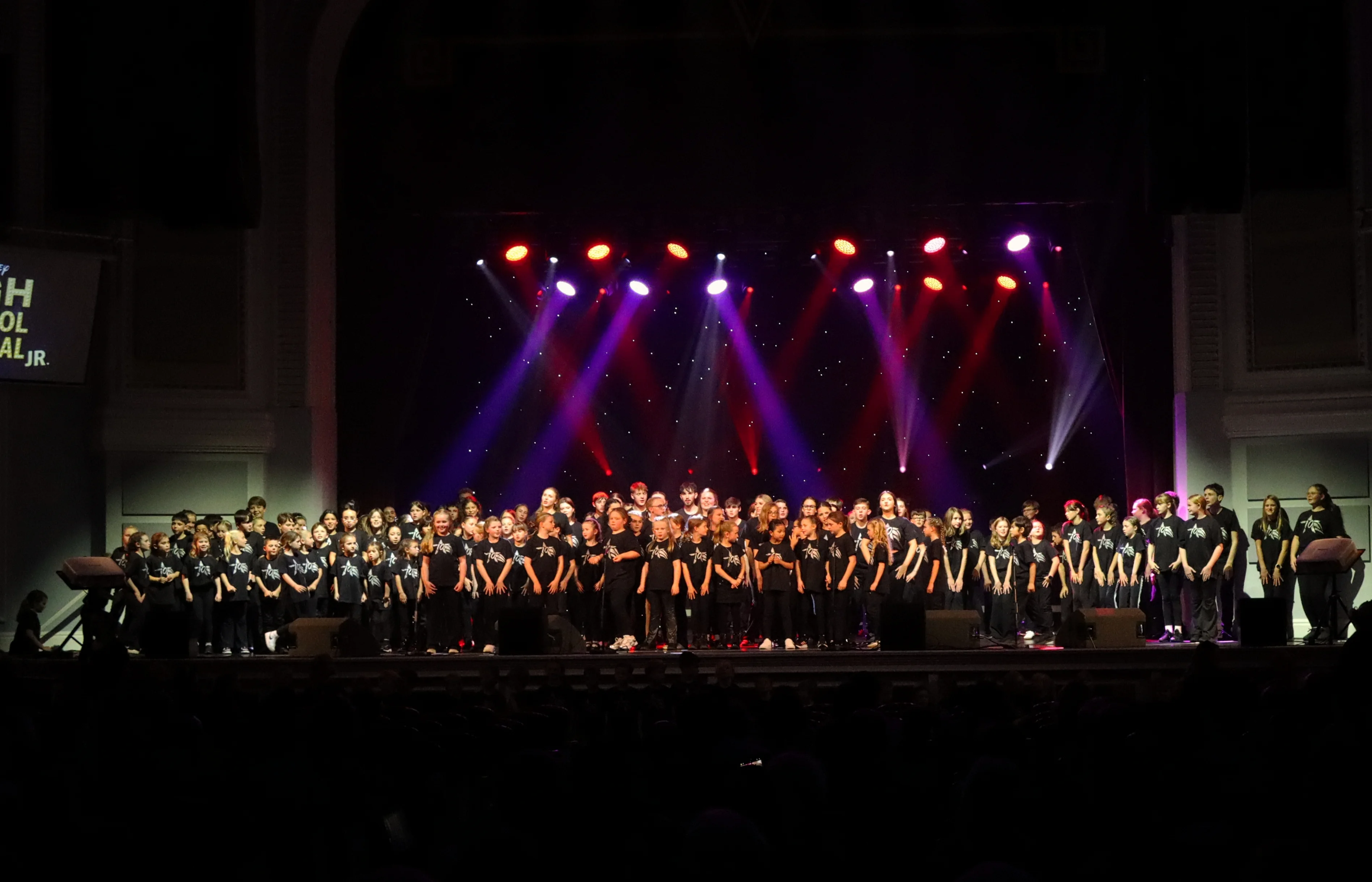 The Arts Hub students performing on stage under coloured lights